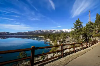 a wooden fence next to a lake with snow covered mountains at Double Suite Diamond Retreat in Incline Village
