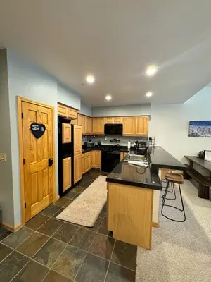 a large kitchen with wooden cabinets and a black counter top at Ski-in Ski-out Family Condo steps from lifts in Kirkwood