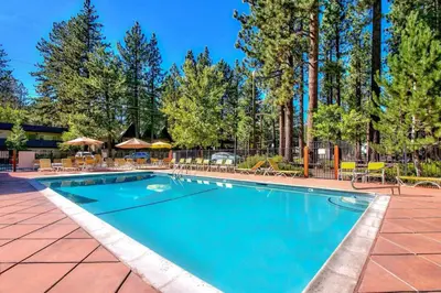 a swimming pool with tables and chairs and trees at Bavarian Village Escape For 6 in South Lake Tahoe