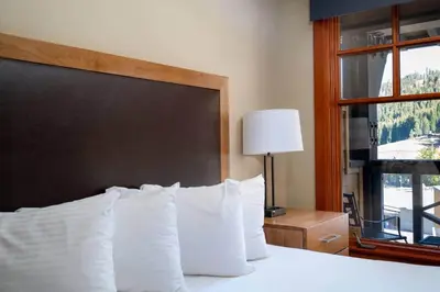 a bedroom with a bed with white pillows and a window at Top Floor Village Ski-In/Ski-Out Condo in Olympic Valley