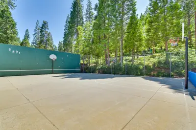 a basketball court with a fence and a basketball hoop at The Green Hideaway Arnold Cabin in the Pines! in Arnold