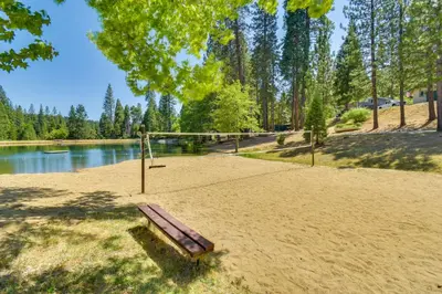 a park bench sitting in the sand next to a lake at Peaceful Escape in the Pines Arnold Cabin with Deck in Arnold