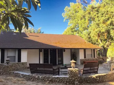 a house with two chairs and a fountain in front of it at Beautiful house by the river and the villager in Fair Oaks