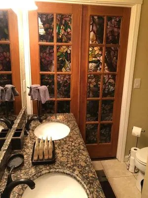 a bathroom with two sinks and a cabinet with wine glasses at The village Inn in Fair Oaks