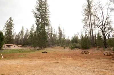a field with two picnic tables and a house at Bright Modern Tiny Retreat with Yoga Dome Near Yosemite, Groveland, California in Groveland
