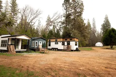 a group of tiny homes parked in a field at Bright Modern Tiny Retreat with Yoga Dome Near Yosemite, Groveland, California in Groveland