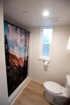 a bathroom with a toilet and a painting on the wall at Bright Modern Tiny Retreat with Yoga Dome Near Yosemite, Groveland, California in Groveland