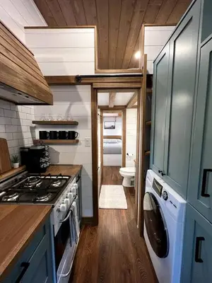 a kitchen with a stove and a washing machine at Cozy Modern Tiny Retreat with Yoga Dome, Garden, and Stargazing in Groveland, California in Groveland