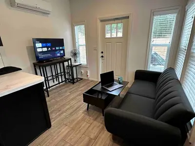 a living room with a couch and a television at Charming Bright Tiny Home with Stargazing & Yoga Dome Near Yosemite, Groveland, California in Groveland
