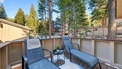 a balcony with two chairs and a table and trees at Pinecone Peak by AvantStay Incline Village Condo Fireplace Balconies Pool Access in Incline Village