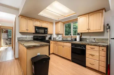 a kitchen with wooden cabinets and a black appliance at Mountain Paradise- Family Cabin w Pool Table in Shaver Lake