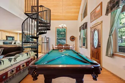 a living room with a pool table and a spiral staircase at Mountain Paradise- Family Cabin w Pool Table in Shaver Lake