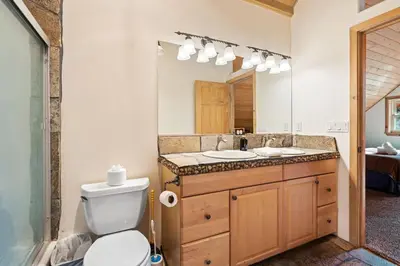 a bathroom with a toilet and a sink and a mirror at Mountain Paradise- Family Cabin w Pool Table in Shaver Lake