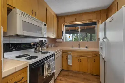 a kitchen with white appliances and wooden cabinets at Mountain View House in Mi-Wuk Village