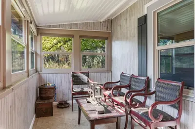 a porch with chairs and a table and windows at Beautiful house by the river and the villager in Fair Oaks