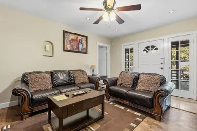 a living room with leather furniture and a ceiling fan at Beautiful house by the river and the villager in Fair Oaks