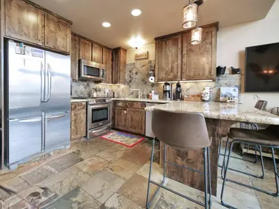 a kitchen with wooden cabinets and a stainless steel refrigerator at Kirkwood Mountainside Cabin Views Walk to Lifts in Kirkwood