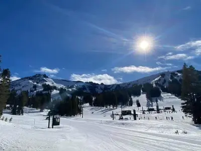 a snow covered ski slope with the sun in the sky at Kirkwood Mountainside Cottage Deck Walk to Lifts in Kirkwood
