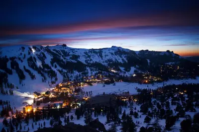 a town in the snow at night with a mountain at Kirkwood Mountainside Cottage Deck Walk to Lifts in Kirkwood