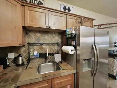 a kitchen with a stainless steel refrigerator and wooden cabinets at Kirkwood Mountainside Cottage Deck Walk to Lifts in Kirkwood