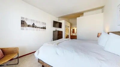 a white bedroom with a large bed and a chair at Snowcreek V #777 condo in Mammoth Lakes