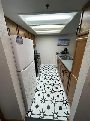 a kitchen with a white refrigerator and a black and white tile floor at The Meadows- Charmed Ski & Relax Studio in Kirkwood