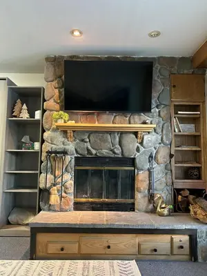 a stone fireplace with a flat screen tv on a wall at The Meadows- Charmed Ski & Relax Studio in Kirkwood