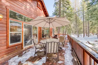 a table with an umbrella on a covered porch at Kindred Pines at Tahoe Donner by Tahoe Getaways - 3BR with Pool Table & HOA in Truckee