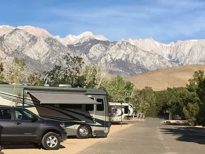 a rv parked in a parking lot with mountains in the background at Boulder Creek RV Resort in Lone Pine