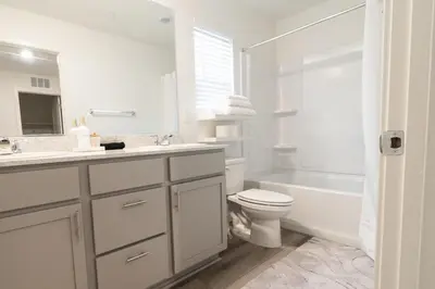 a white bathroom with a toilet and a sink at Beautiful Modern Home with Outdoor Patio and BBQ Grill in Elk Grove