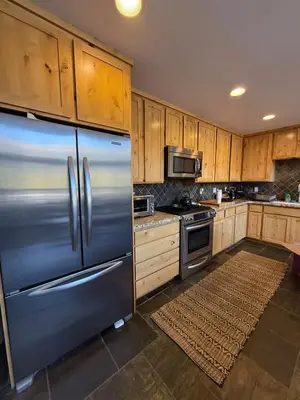 a kitchen with a stainless steel refrigerator and wooden cabinets at Kirkwood Resort between Village & Timber Creek in Markleeville