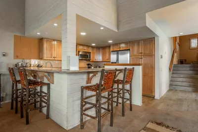 a kitchen with wooden cabinets and bar stools at Bridges 3 in Mammoth Lakes