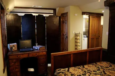 a bedroom with a bed and a desk with a laptop on it at Charming vintage village house in Fair Oaks