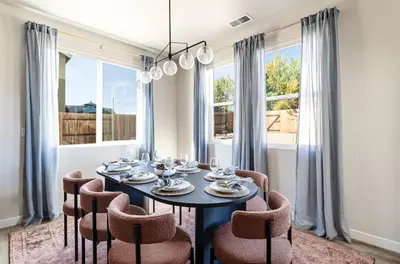 a dining room with a table and chairs and windows at Dusty Sage Hollow in Fernley