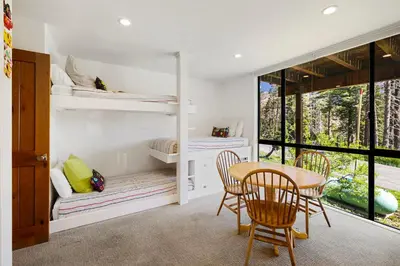 a room with bunk beds and a table and chairs at Alpine Meadows Basecamp in Alpine Meadows