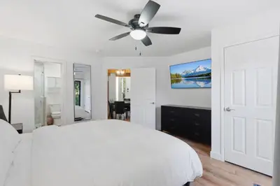 a white bedroom with a white bed and a ceiling fan at Shaver Escape Hot Tub Cabin Retreat with AC in Shaver Lake