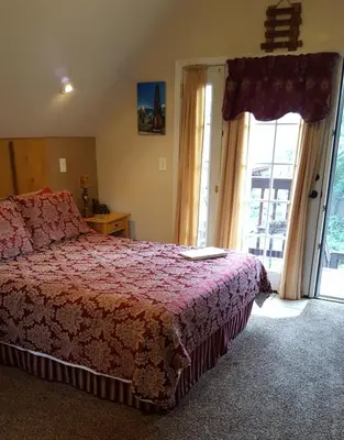 a bedroom with a bed with a red comforter at Nature's Inn Bed and Breakfast in Ahwahnee