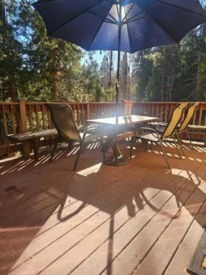 a table and chairs and a blue umbrella on a deck at The Cozy Knotty Pine Enchantment Retreat in Long Barn