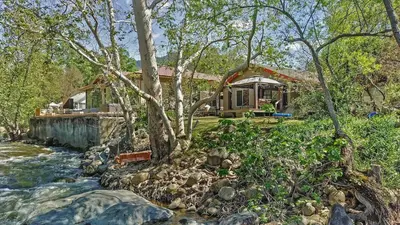 a house next to a river with a house at Cozy Riverfront Home with EV charger in Three Rivers