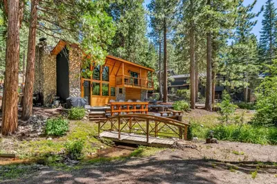 a log cabin in the woods with a bridge in front at Little Bridge Lodge Stateline - Small Dogs Ok in Stateline