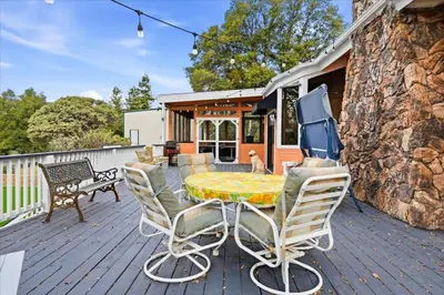 a patio with a table and chairs on a deck at Fun Getaway with Golf HotTub Volleyball and more in Oakhurst