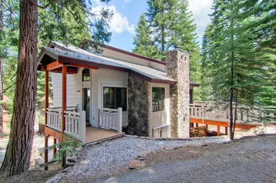 a small house with a porch in the woods at Ahwahnichi Lodge in Yosemite West