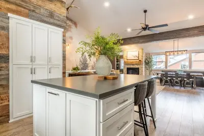 a kitchen with white cabinets and a island with a plant at Luxury Helios Retreat by the Village- Apres Ready in Mammoth Lakes