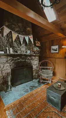 a living room with a fireplace and a chair at Campo Carnelian in Carnelian Bay