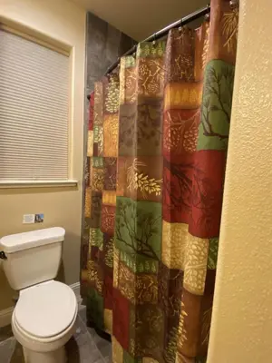 a bathroom with a toilet and a shower curtain at Yosemite's Inn the Woods in Ahwahnee