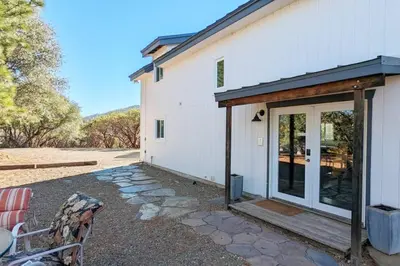 a white house with a sliding glass door at Cozy Woodworker's Cabin, 26 miles to Yosemite! in Midpines
