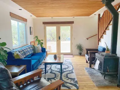 a living room with a blue couch and a stove at Cozy Woodworker's Cabin, 26 miles to Yosemite! in Midpines