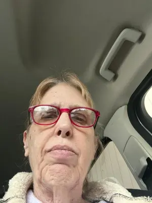 an older woman with red glasses sitting in a vehicle at Rancho Grand Mobile Home Park in Atwater