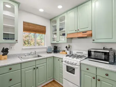 a kitchen with green cabinets and a stove top oven at Forest Retreat that accommodates 29 people near Yosemite & Bass Lake in Oakhurst