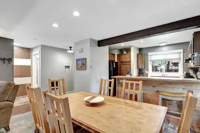 a kitchen and dining room with a wooden table and chairs at Mountain Condo | Spa Pool and Ski Shuttle Access in Mammoth Lakes
